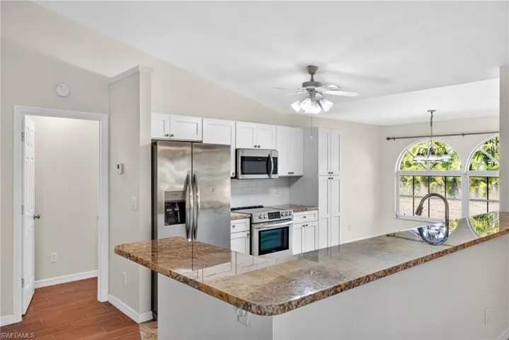 Kitchen featuring stainless steel appliances, tasteful backsplash, white cabinets, a peninsula, and ceiling fan