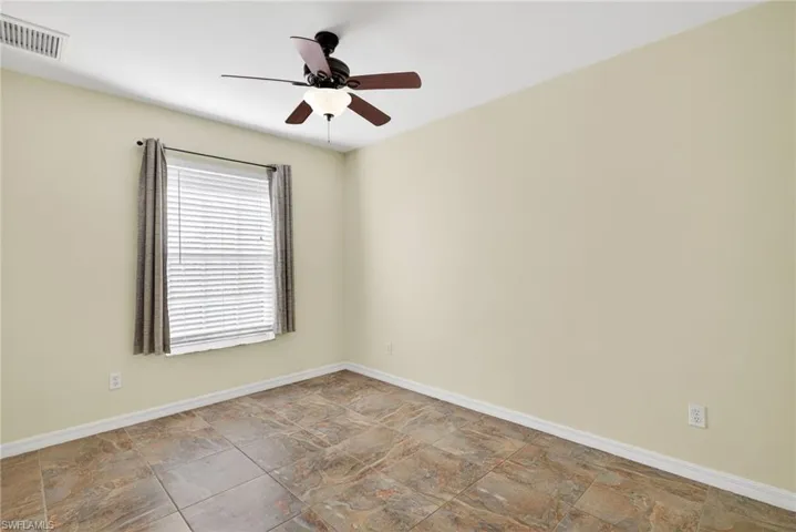 Unfurnished room featuring ceiling fan and stone finish floors