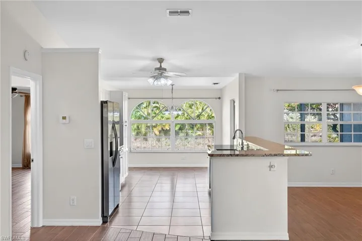 Kitchen with a ceiling fan, stainless steel fridge, dark stone countertops, suspended lighting, and light wood-style floors