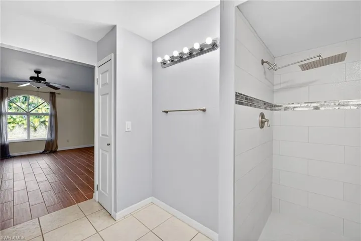 Full bathroom with ceiling fan, a tile shower, and light tile patterned floors