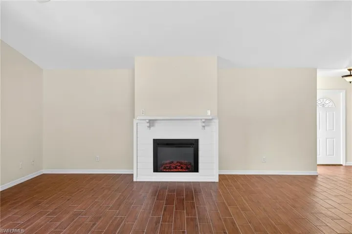 Unfurnished living room with wood finish floors and a glass covered fireplace