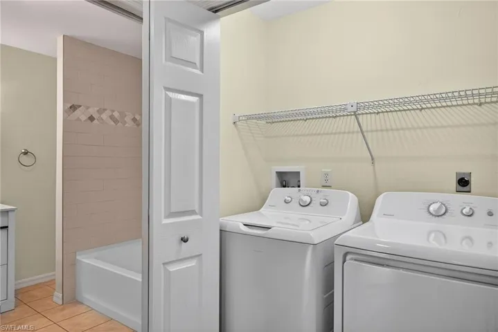 Laundry area featuring light tile patterned floors and washing machine and clothes dryer