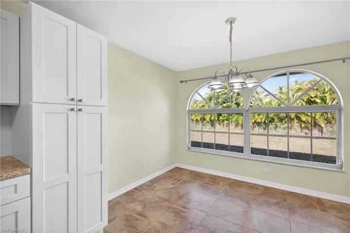 Unfurnished dining area featuring a chandelier and baseboards