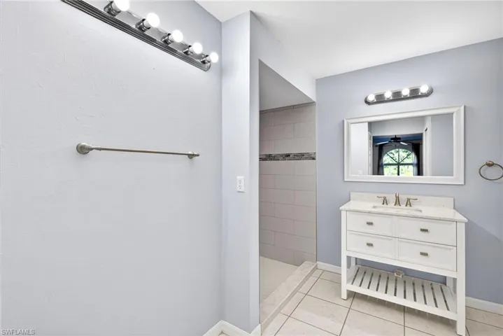 Full bathroom with vanity, a tile shower, and light tile patterned floors