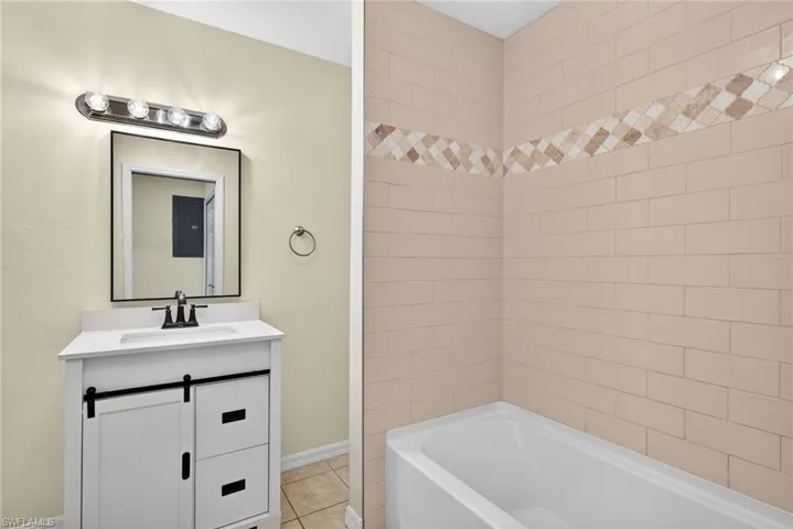 Bathroom with vanity, shower / tub combination, and light tile patterned floors