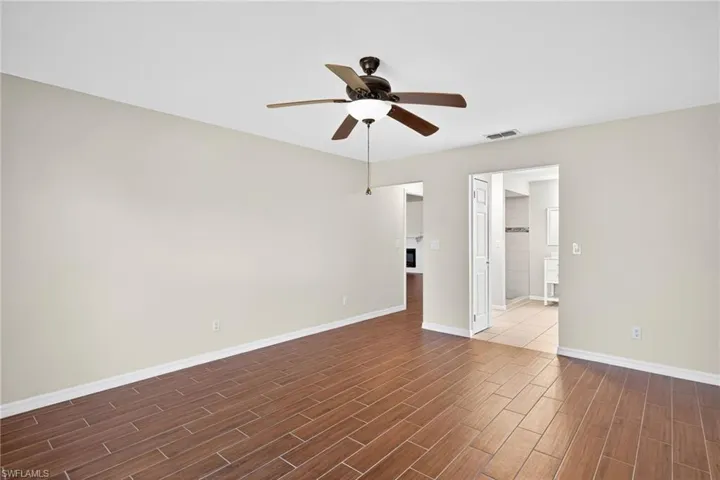 Empty room with a ceiling fan and wood tiled floors