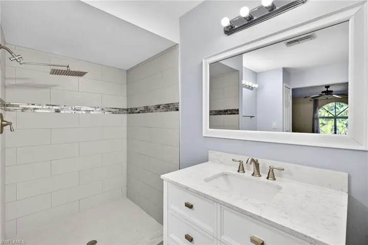 Bathroom with vanity, tiled shower, and ceiling fan