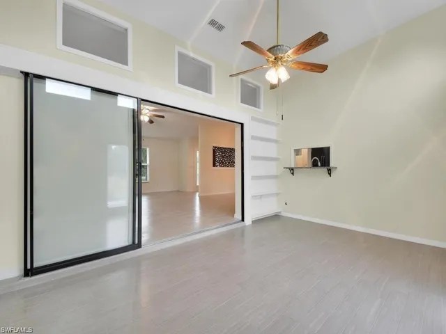Unfurnished room featuring ceiling fan, light wood-style floors, and lofted ceiling