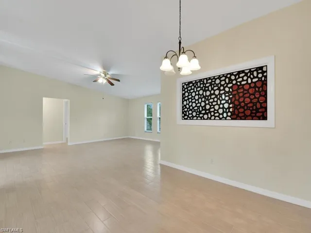 Empty room with suspended lighting, light wood-style flooring, and a ceiling fan