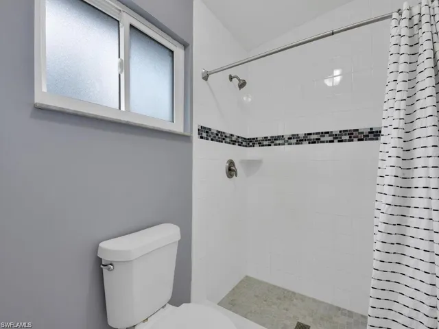 Full bath with toilet and a stall shower