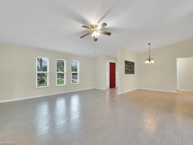 Spare room with suspended lighting, ceiling fan, and light wood-type flooring