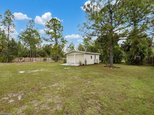View of yard with a detached storage, an outbuilding, and view of wooded area