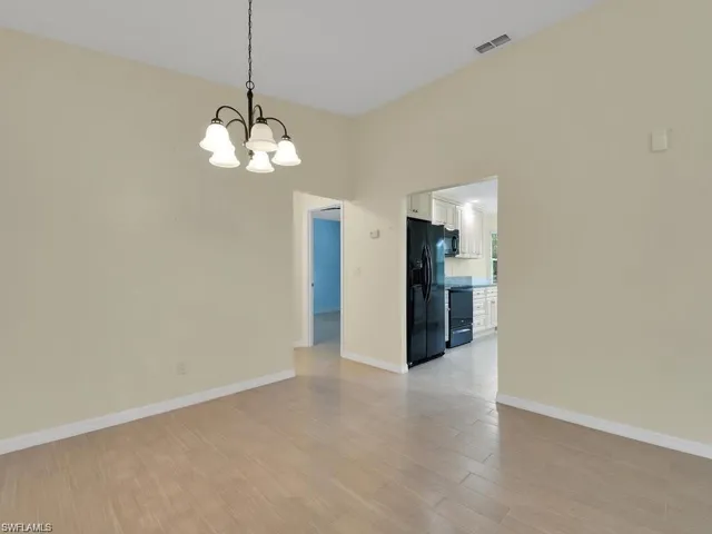 Spare room with hanging lights and light wood-style flooring