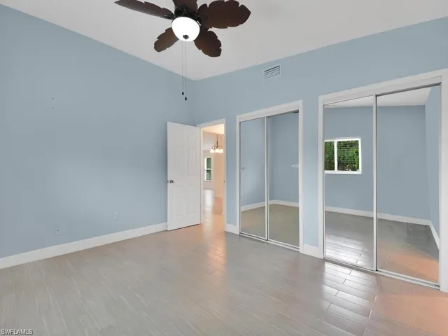 Unfurnished bedroom with multiple closets, a ceiling fan, and light wood-style floors