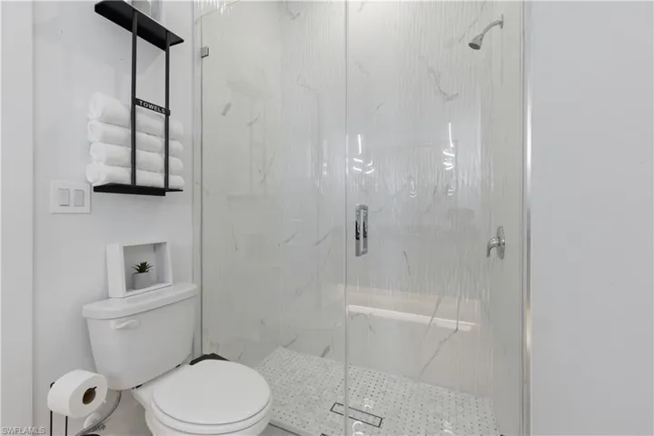 Bathroom featuring toilet and a marble finish shower