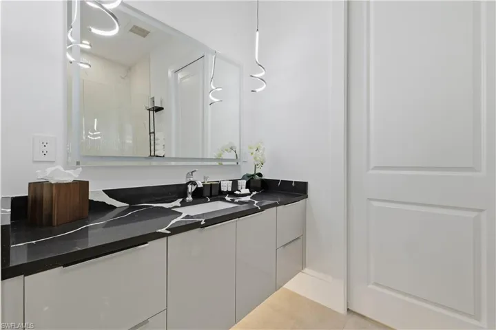 Full bath featuring vanity, light tile patterned floors, and a shower