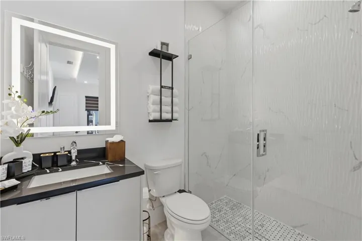 Bathroom featuring vanity and a marble finish shower