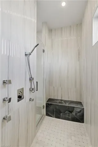 Full bath with a marble finish shower and recessed lighting