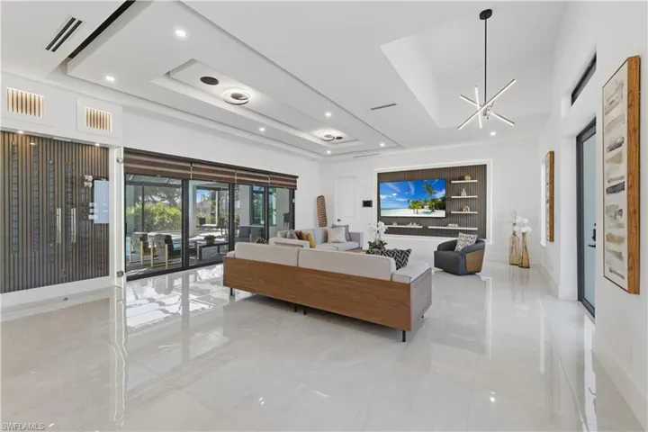Living room featuring a tray ceiling and suspended lighting