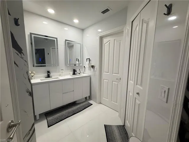 Full bathroom with double vanity, a closet, light tile patterned floors, and recessed lighting
