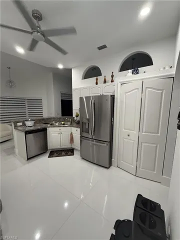 Kitchen with white cabinets, appliances with stainless steel finishes, light tile patterned floors, dark stone countertops, and recessed lighting