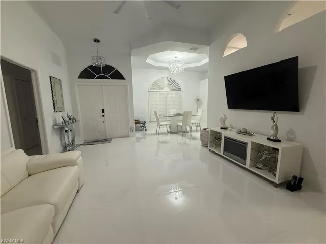 Living area with light tile patterned flooring, a chandelier, and a raised ceiling