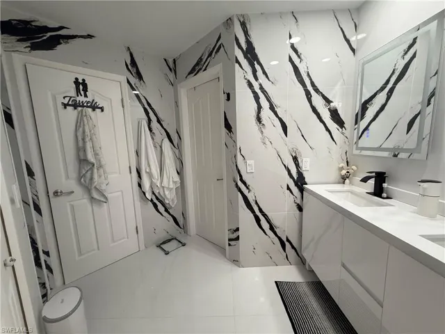 Bathroom featuring stone wall, double vanity, and tile walls
