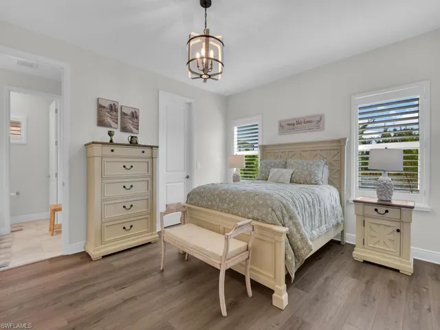 Bedroom with multiple windows, a chandelier, and light wood finished floors