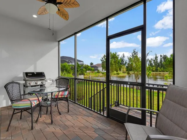 Sunroom / solarium with ceiling fan, a water view, a textured wall, and recessed lighting