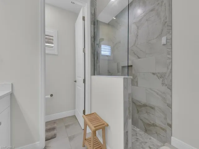 Full bath with a marble finish shower, vanity, and light tile patterned flooring