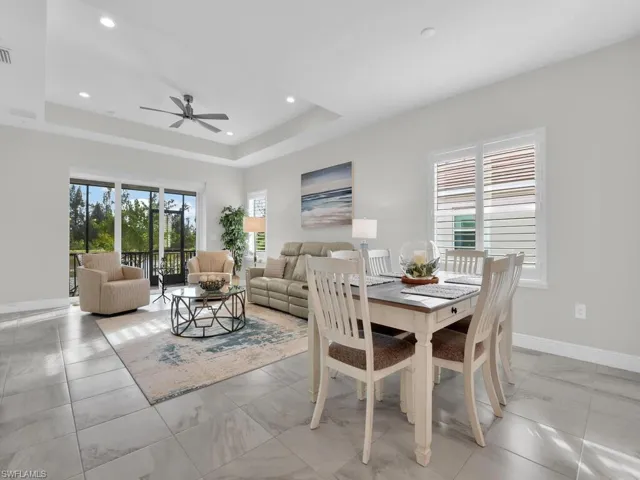 Dining space featuring healthy amount of natural light, a tray ceiling, recessed lighting, and a ceiling fan