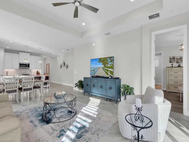 Living room with recessed lighting, a tray ceiling, and a ceiling fan