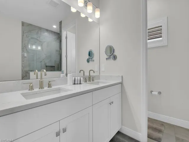Full bathroom with a marble finish shower, double vanity, and light tile patterned floors