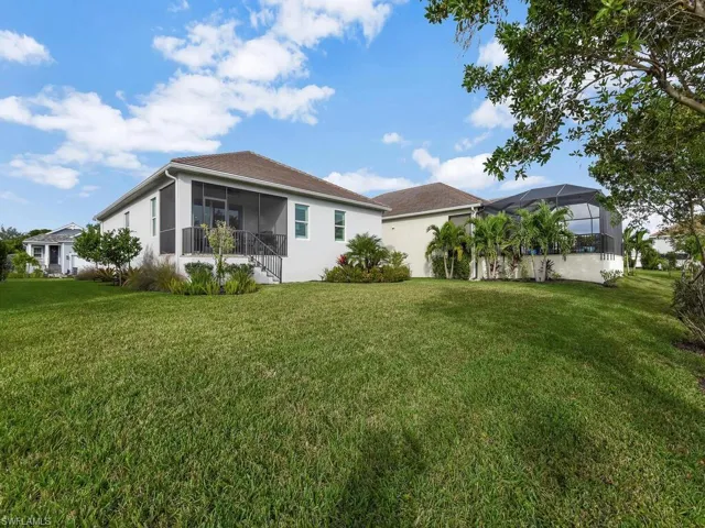 Rear view of property with a yard, a sunroom, a lanai, and stucco siding