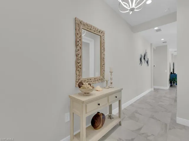 Corridor with light marble finish floors, recessed lighting, and a chandelier