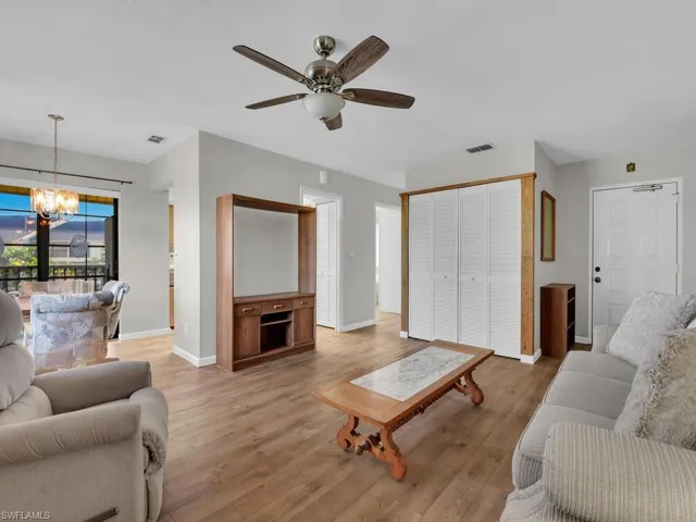 Living area featuring light wood-style floors, a chandelier, and ceiling fan