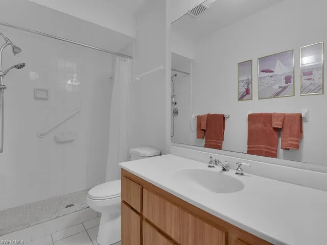 Bathroom featuring light tile patterned flooring, tiled shower, and vanity