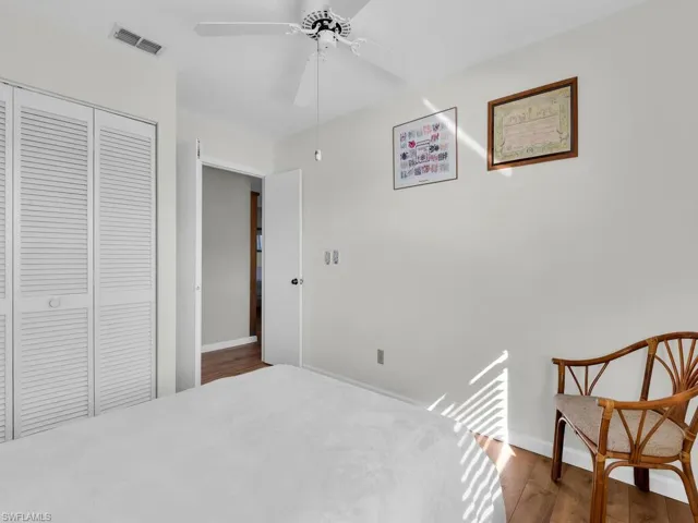 Bedroom with dark wood-style floors, a closet, and a ceiling fan