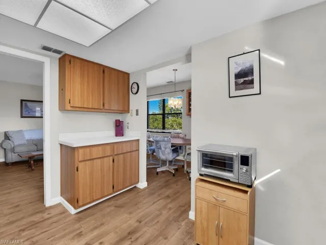 Kitchen with light countertops, light wood-type flooring, brown cabinets, hanging light fixtures, and a chandelier