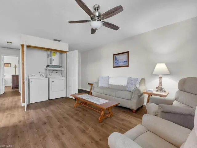 Living room featuring wood finished floors, a ceiling fan, and independent washer and dryer