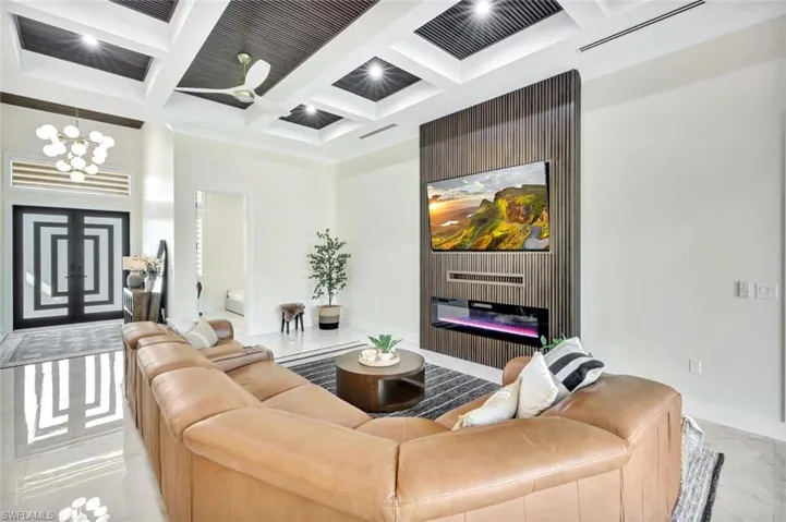 Foyer and Living room with coffered ceiling, a glass covered fireplace, beam ceiling, and a chandelier