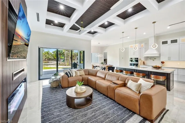 Living area featuring coffered ceiling, beamed ceiling, a ceiling fan, a high end fireplace, and a towering ceiling