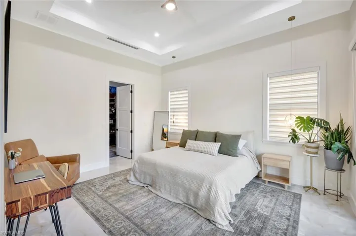 Bedroom with a raised ceiling, a ceiling fan, and a walk in closet
