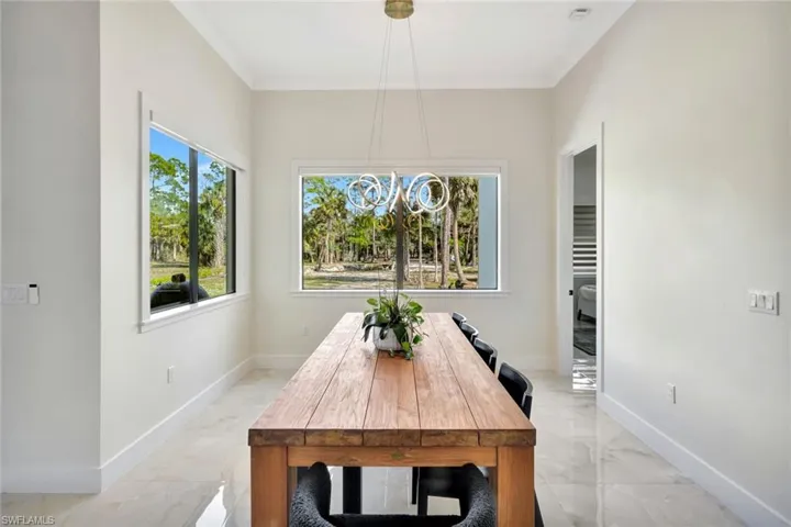 Dining area with light marble finish floors and a chandelier