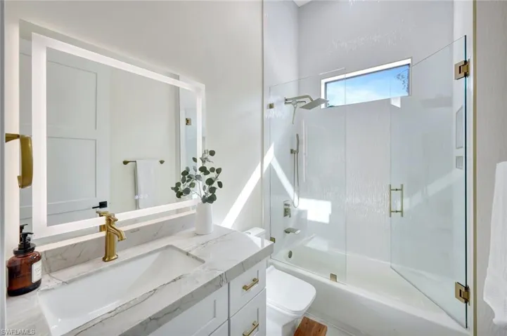 Bathroom with shower / bath combination with glass door and vanity