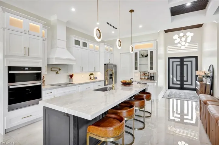 Kitchen with glass insert cabinets, a kitchen bar, white cabinets, light stone counters, and ornamental molding