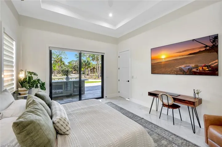 Bedroom with access to exterior, ceiling fan, a tray ceiling, and a towering ceiling