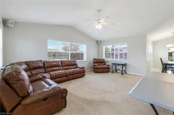 Carpeted living area with lofted ceiling, a ceiling fan, and a chandelier