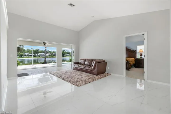 Living area with vaulted ceiling, marble finish floors, ceiling fan, and a water view