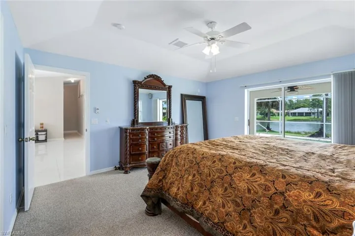 Bedroom with access to exterior, light colored carpet, ceiling fan, and vaulted ceiling
